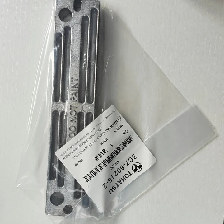 Metal component with label in clear plastic packaging on a white background